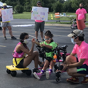 Volunteers helping a young girl in a walker at the annual Tri My Best Triathlon - Kenosha